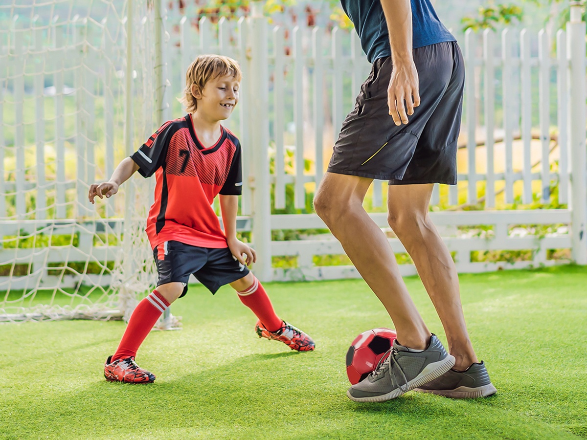 Young boy having fun playing soccer with his dad