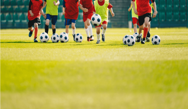 line of young soccer players dribbling soccer drill