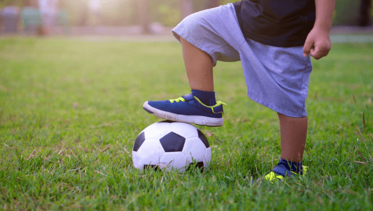 young boy with soccer ball in field