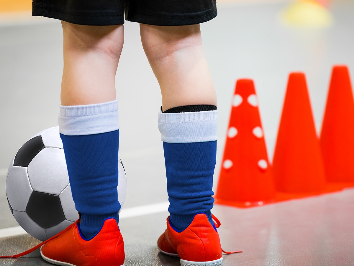 youth soccer player feet next to a ball and orange cones